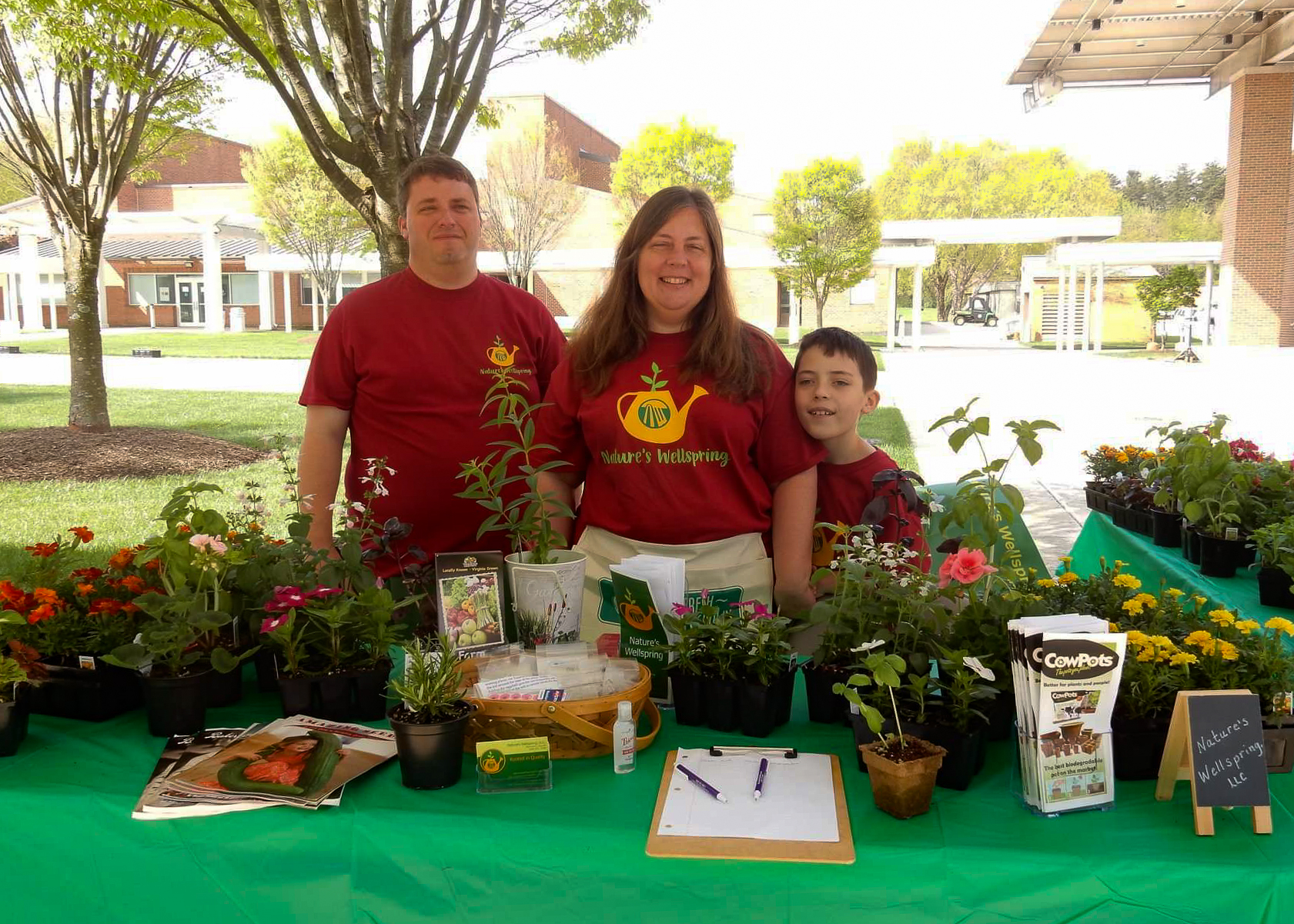 A Family Stands At A Farmer's Market Booth.