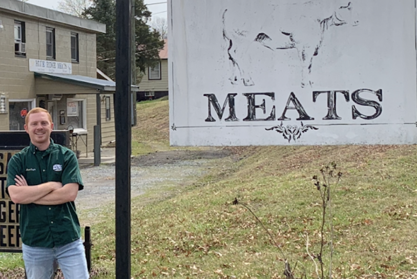 Matt Coyle Stands Next To A Meat Sign.