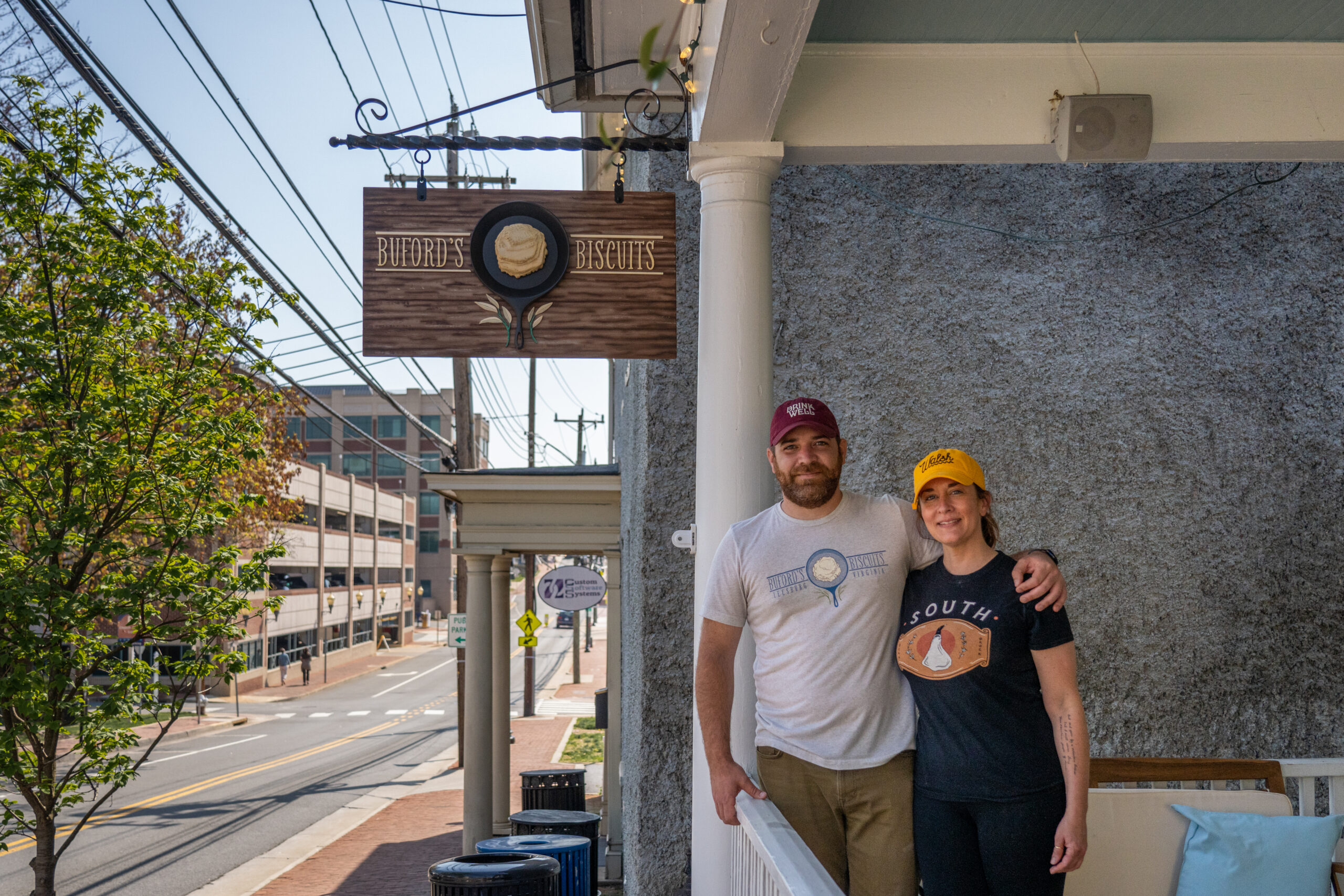 A Man And Woman Stand Together In Front Of Their Restaurant.