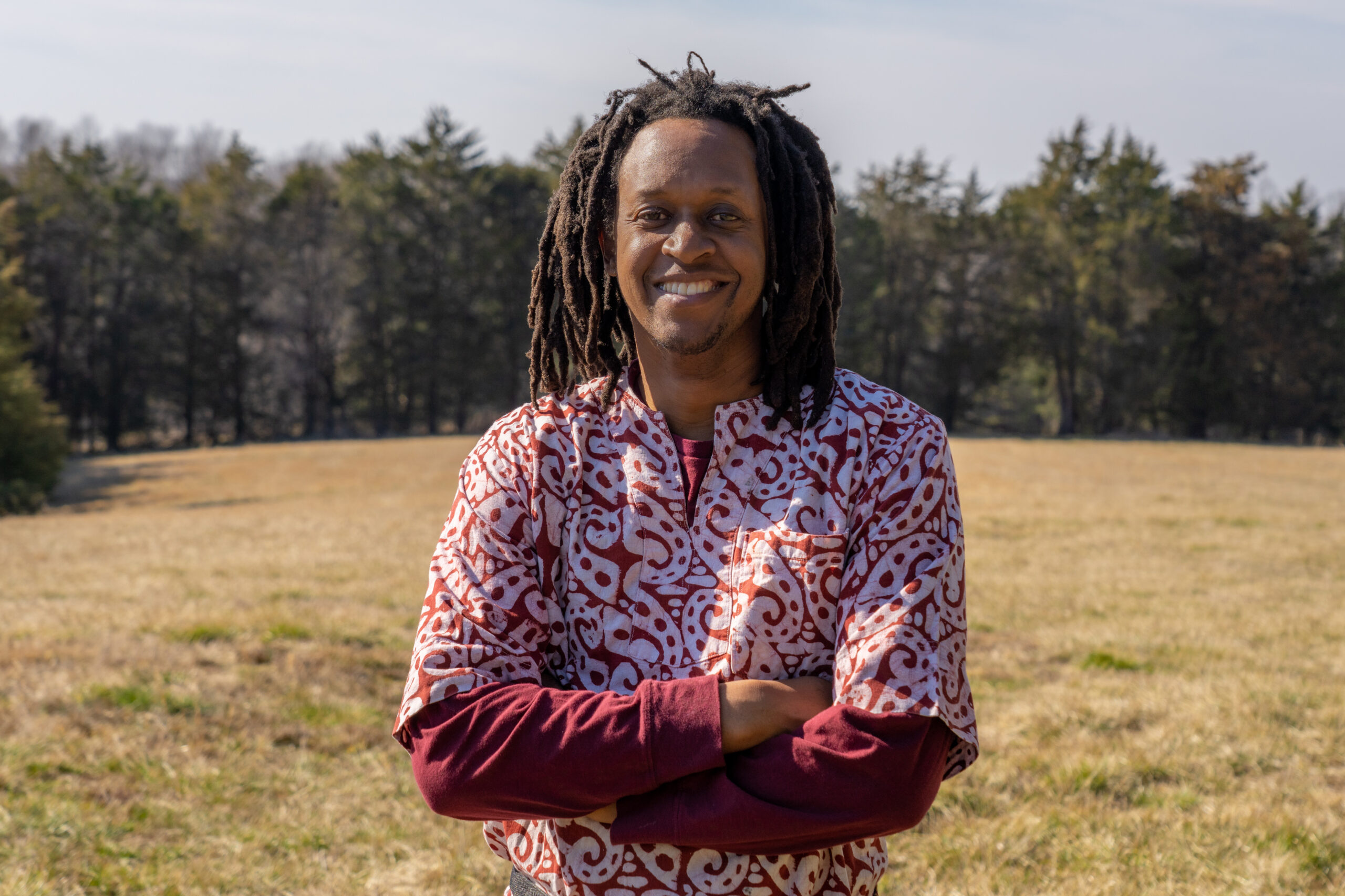 A Man Stands With His Farm Behind Him.