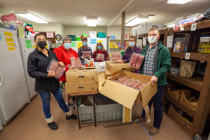 Volunteers hold packages of donated beef at a table.